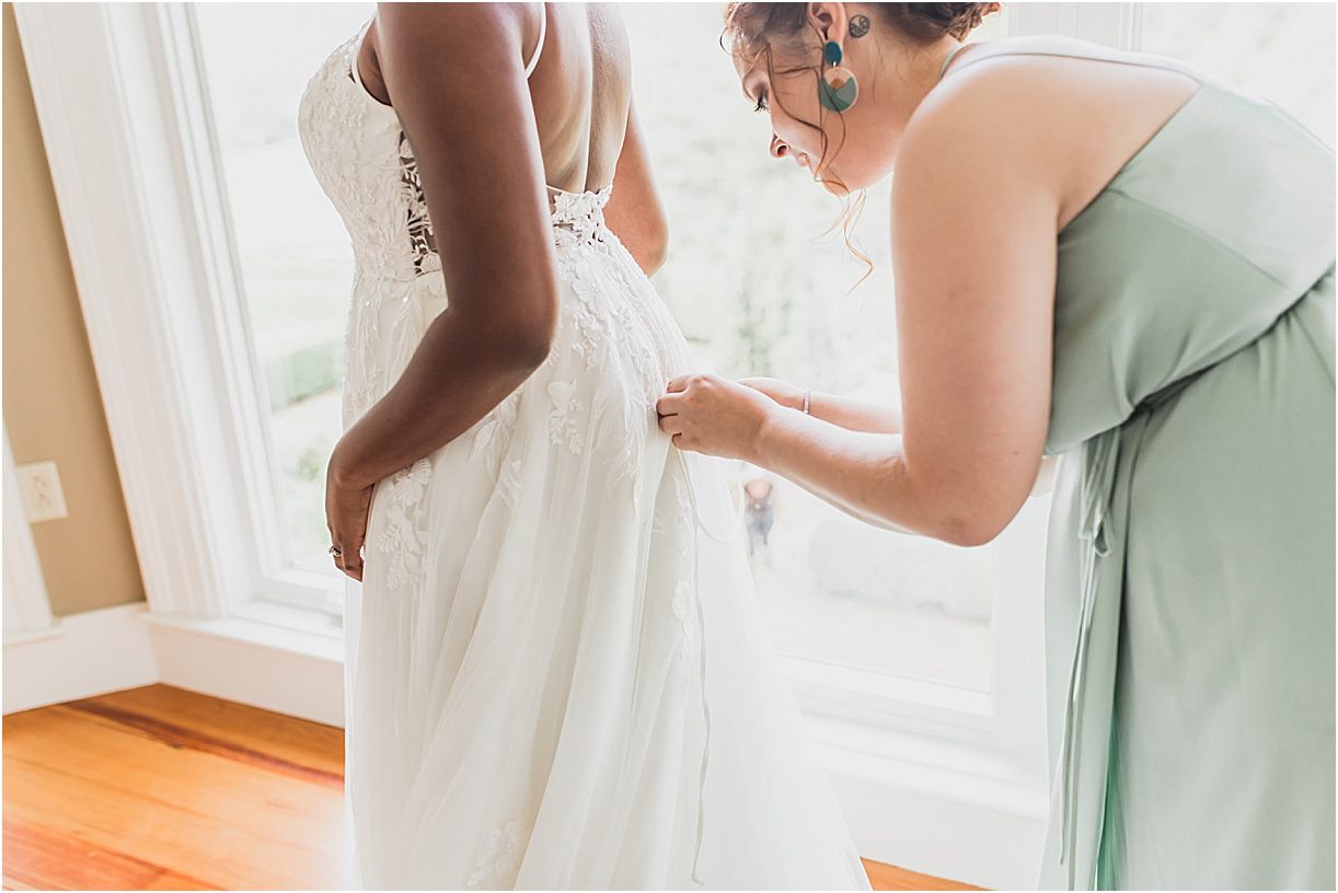 Bridesmaid Zipping up Wedding Gown of Bride