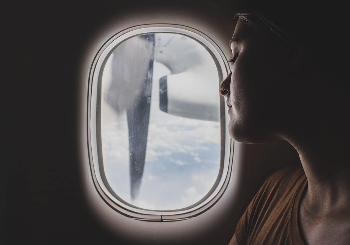 Woman Looking Out Plane Window Carry-on Packing