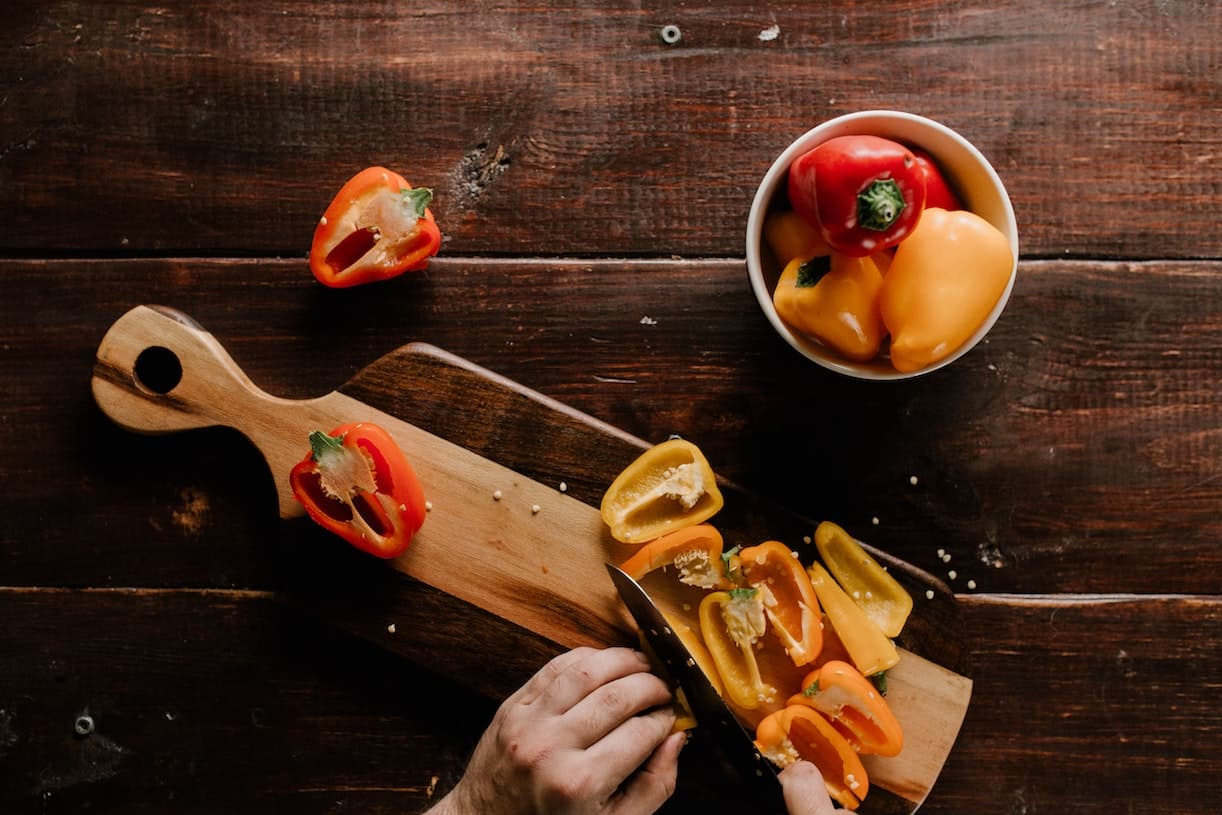 Man Cutting Peppers on Wooden Board